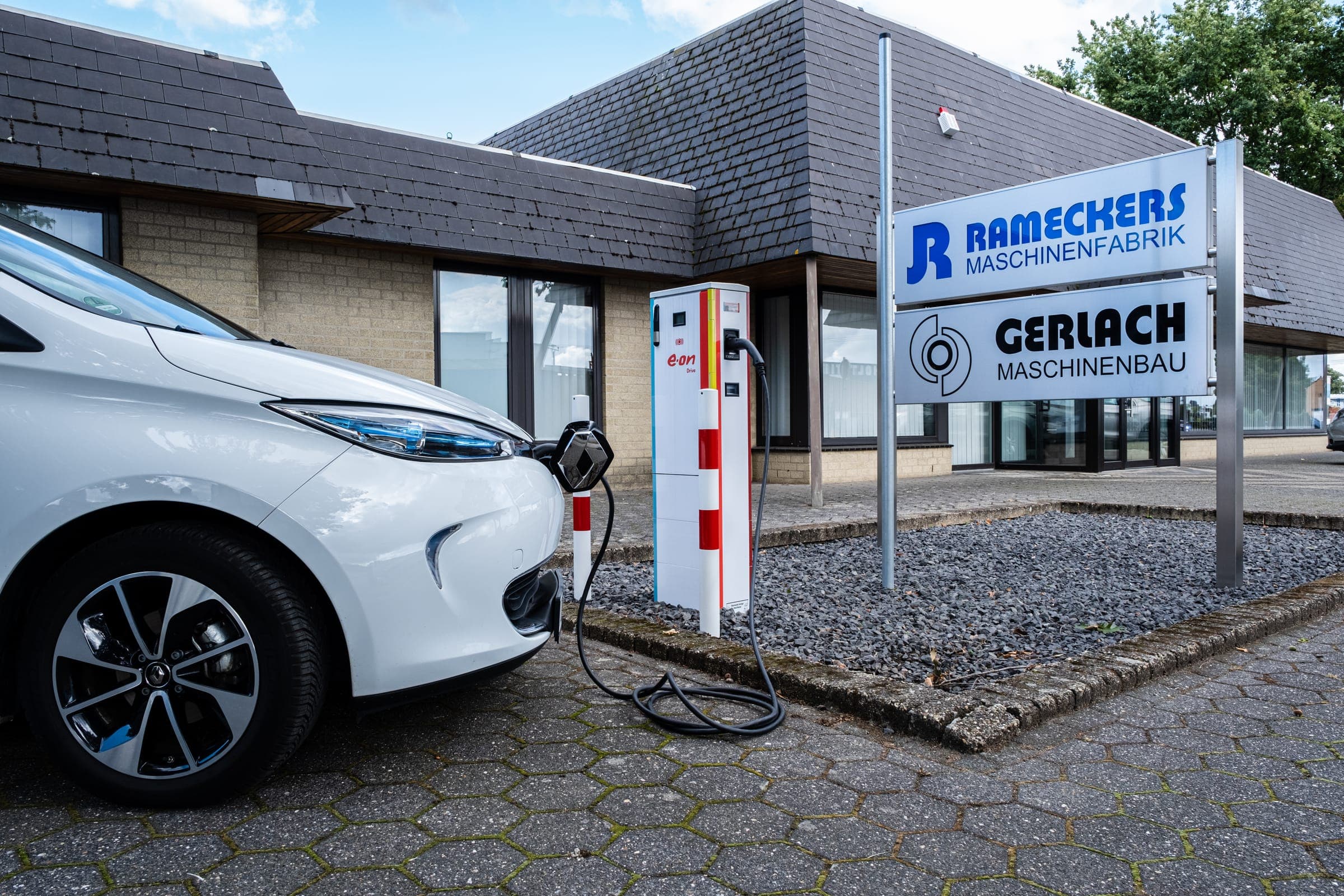 Elektrofahrzeug an der Ladesäule vor dem Gebäude von Rameckers Maschinenfabrik und Gerlach Maschinenbau