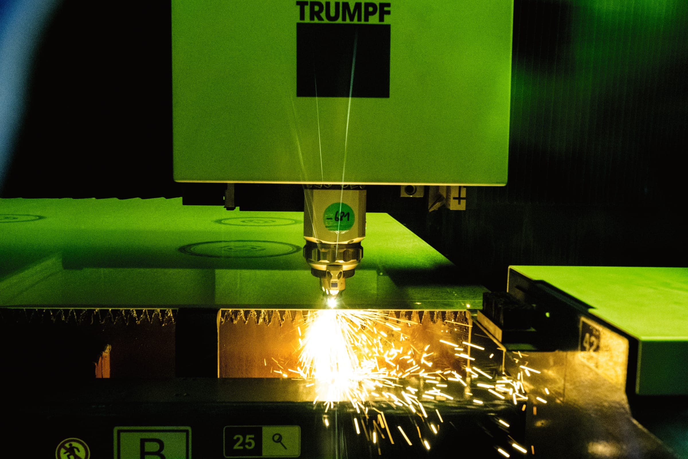 Laserschneidkopf einer Trumpf-Anlage beim Schneiden von Blech mit Funkenflug